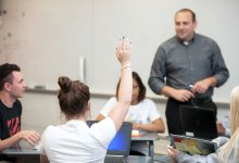 Student with hand raised in class at Smyrna High School.