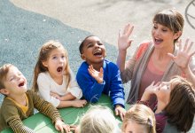 Kindergarten teacher plays a game outside with her students