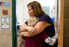 A teacher hugs her student.