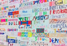 A school bulletin board covered with many hand-decorated words students used to describe school, including "fun," "confusing," "boring," and "important"